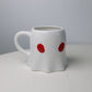 cup in a ghost shape with tiny red eyes